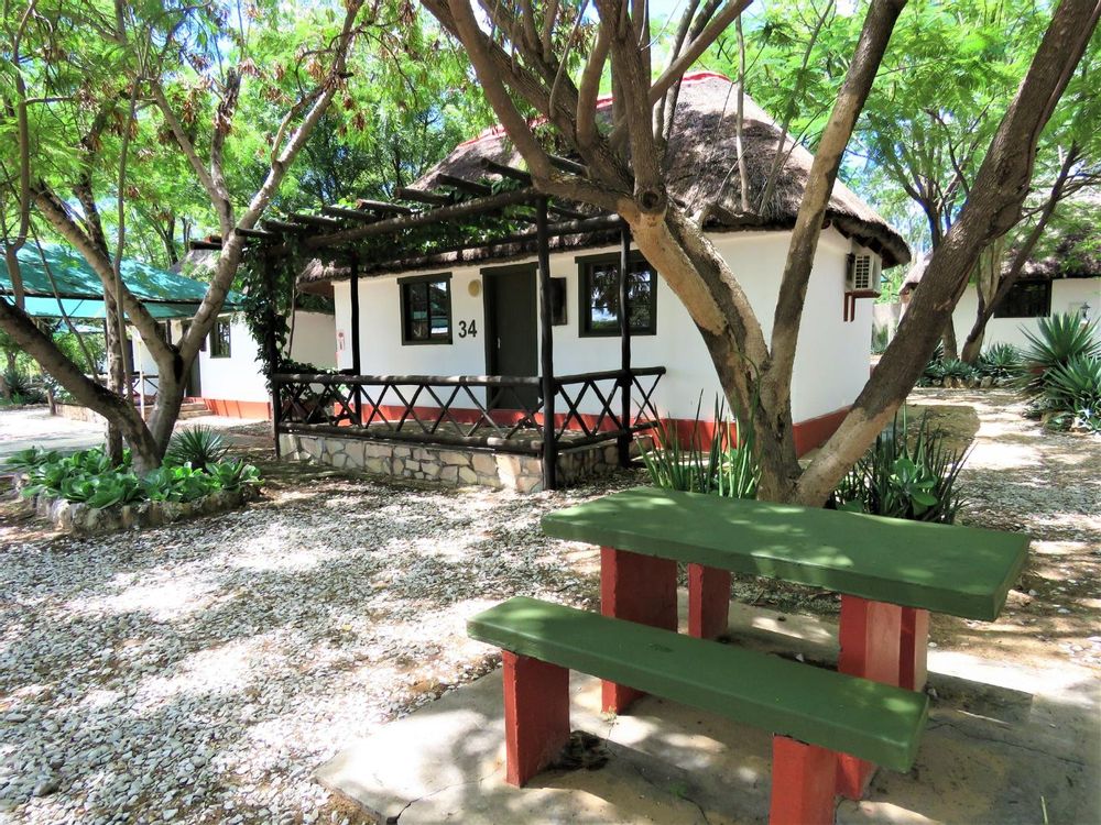 One of the chalets with outside seating and a carport with shade net