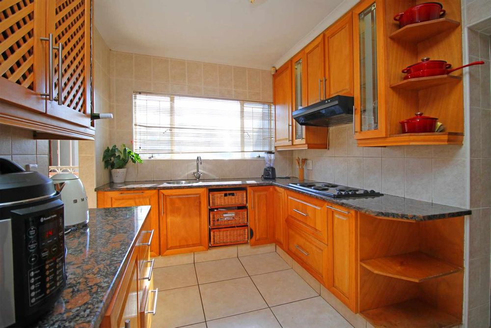 Kitchen with modern natural textures and a blend of warm wood tones with caramel coloured granite tops. Key Features include natural wood elements in oak providing warmth and timeless elegance.  The natural stone kitchen tops add to the modern aesthetic for a luxurious, contemporary look. 