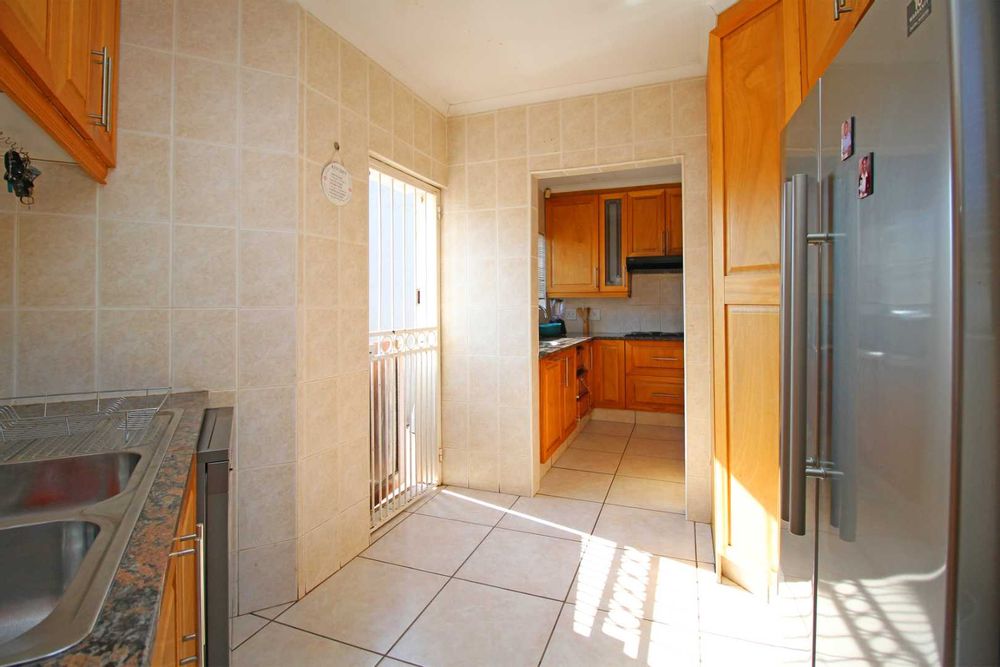 Kitchen Scullery with Granite Tops and a designated area for the Double Door Refrigerator. The Large Pantry is also conveniently placed in the Scullery for easy food preparation on the Granite Tops.  The Scullery is interlinked with the Garage for a practical and convenient grocery door providing easy access from the garage to the Pantry.  This multifunctional feature in the kitchen does double duty with a well-designed scullery and pantry for food storage, freezer, small apliance hub, sink and effective kitchen storage.  This zone is a huge asset in this home because of its functionality and for hassle-free unloading of groceries. 