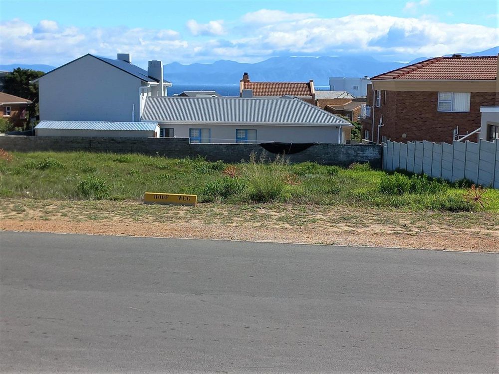 Our Plot in front of us. In between us & the Sea, is a House with a Double storey part on our left & Ground level part on right. We overlook the wide ground level part.