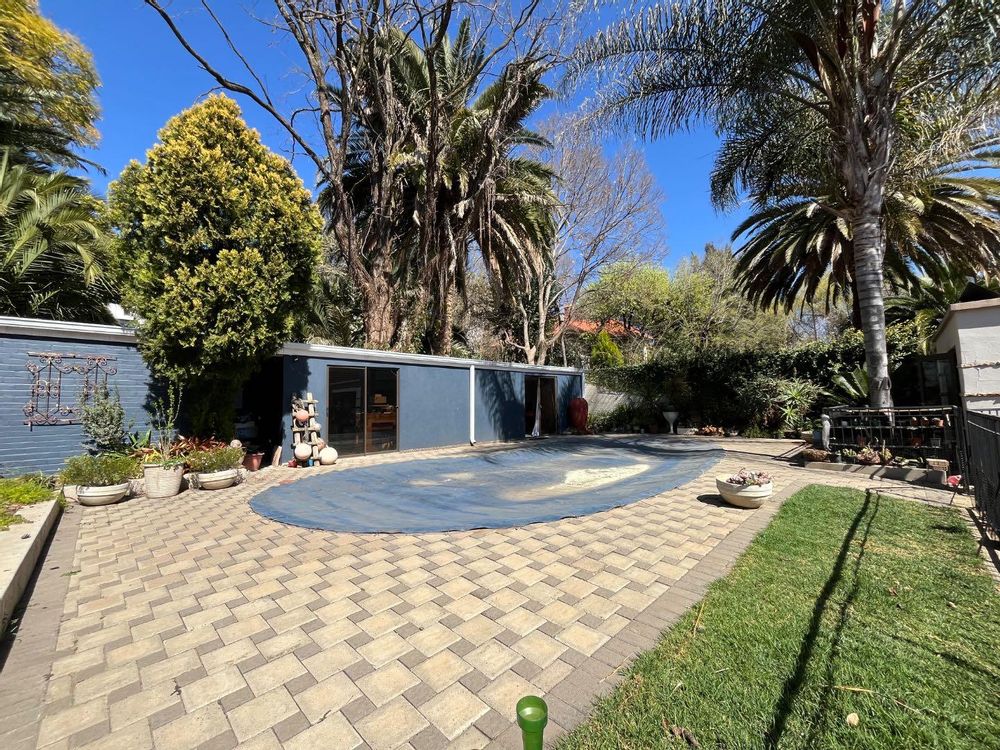 Tree filled garden with swimming pool.