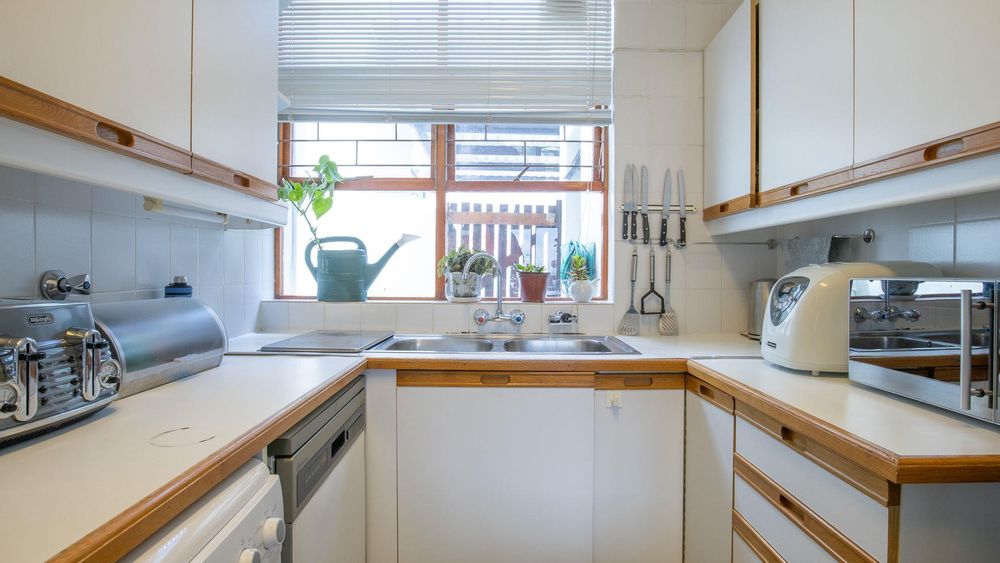 Tiled kitchen with lots of cupboard space overlooking drive way