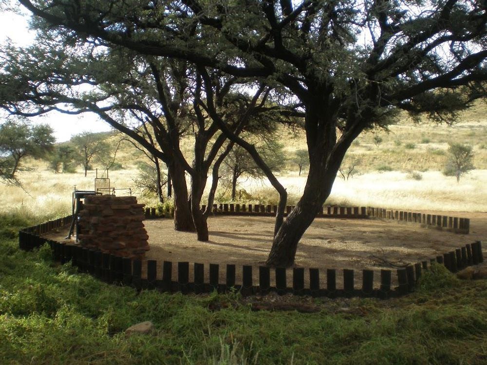 Camp site with fire place and basin which is covered in shade