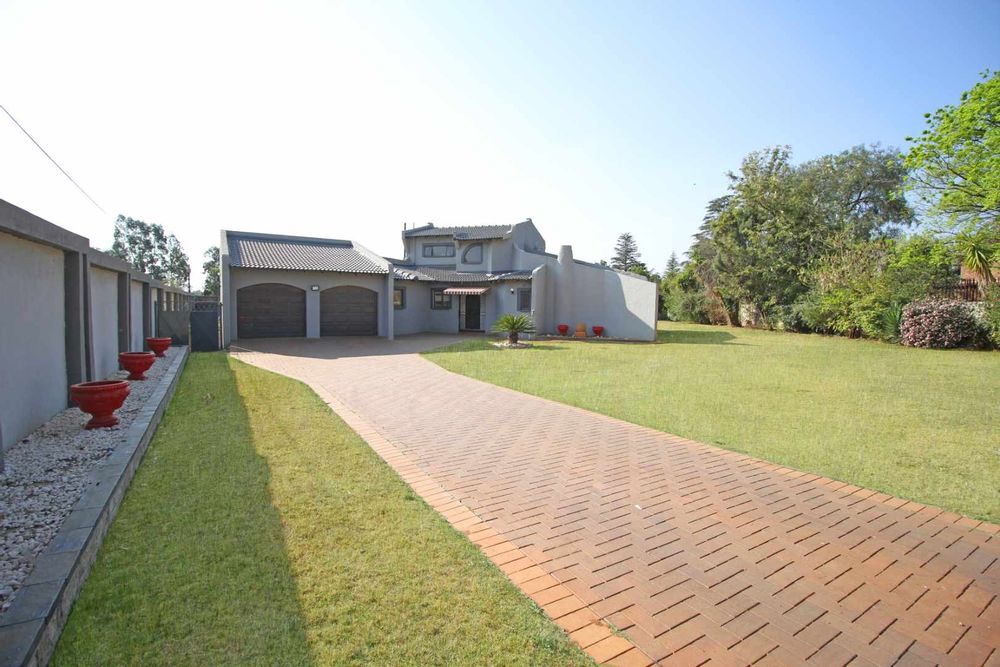 Front View of the Massive 2304m² Erf of this Property with it's Automated Double Timber Garage Doors, Paved Driveway and the Expansive Garden Terrace.  The Newly Built Fence is particularly attractive at night with down lights that lights-up the Driveway and Garden Terrace.  
