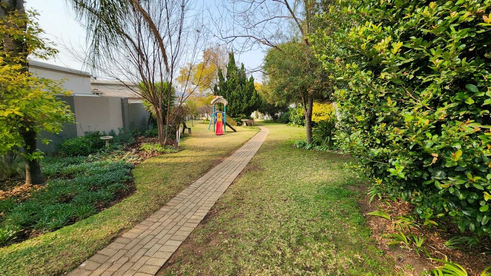 Large lush open communal park with paved exercise path