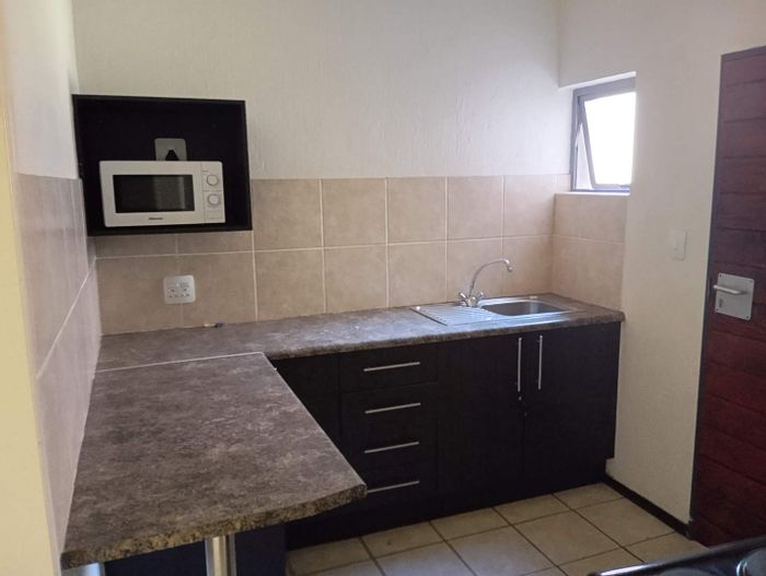 1-Bedroom Apartment To Rent in Ruimsig with security, kitchenette, and laundromat access.