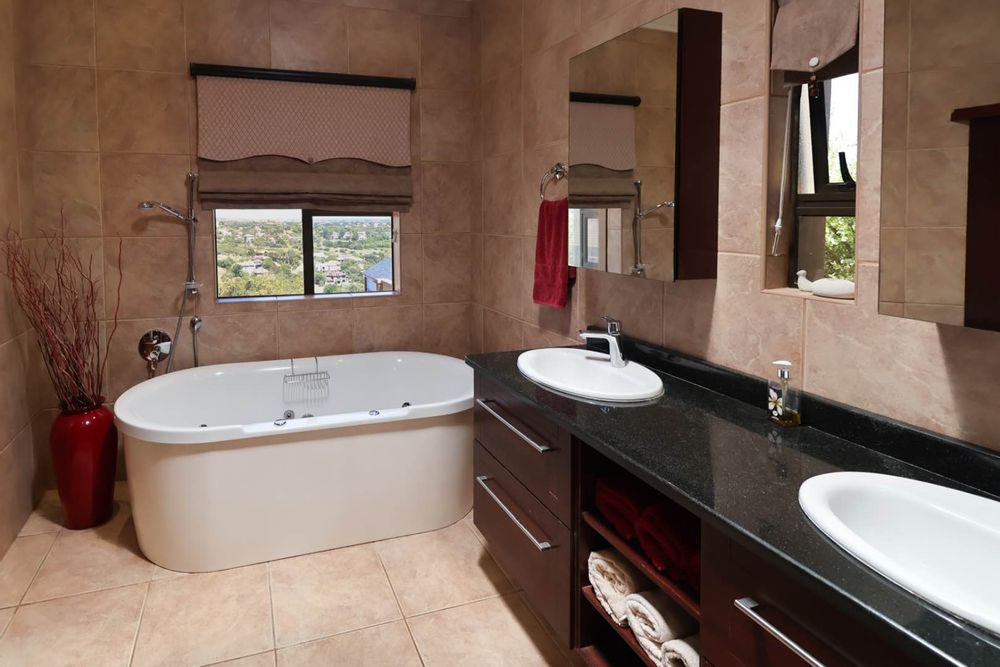 Close-up of bath and double vanity.  Bathroom offers view of the estate.