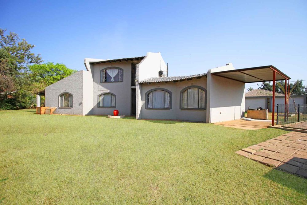 View of the Double Storey Property from the Entertainment Area with Built-In Picnic Table and Multiple Seating located next to the Swimming Pool in this expansive 2304m² Erf with Garden Terraces right around.  The Carport is ideal for an Overlanding Vehicle, or Caravan, or Boat or just for a third family car.