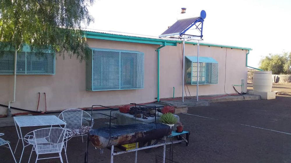 Main house- back yard view of the house with outside seating area and a tree for shade. Also a great spot for an outside BBQ