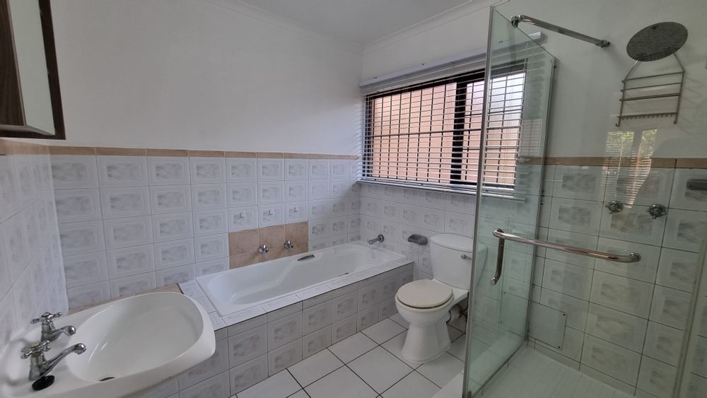 Ensuite bathroom with bath, shower, wash basin, cupboard, and blinds