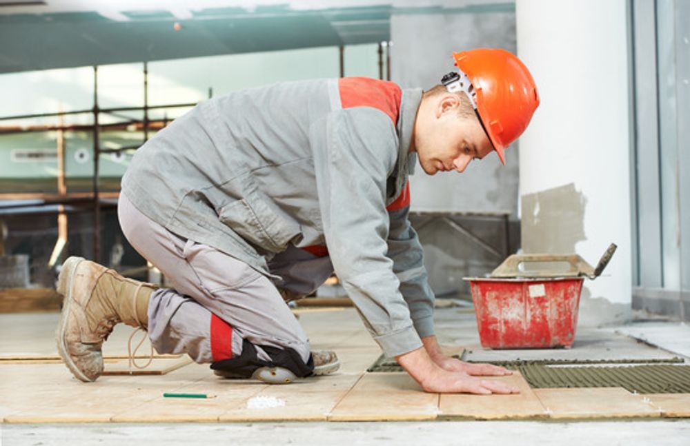 Industrial tiler builder worker installing floor tile at repair renovation work